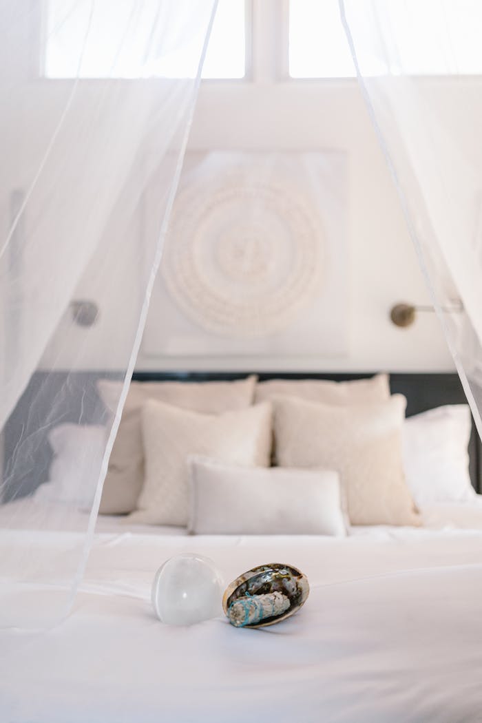 A peaceful bedroom with white pillows and healing crystals creating a calming atmosphere.