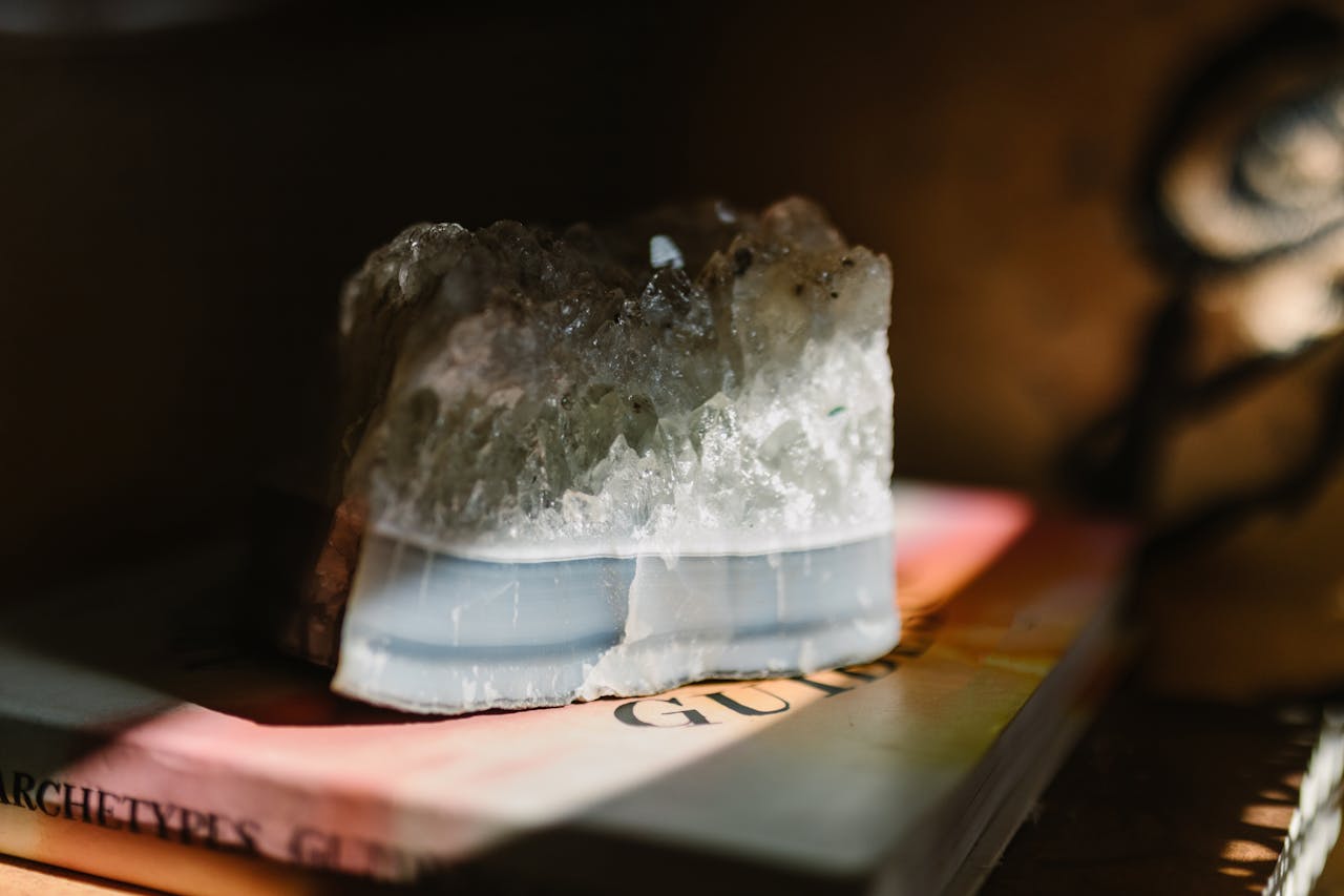 A beautiful crystal stone resting on a book, illuminated by soft sunlight, creating a serene atmosphere.