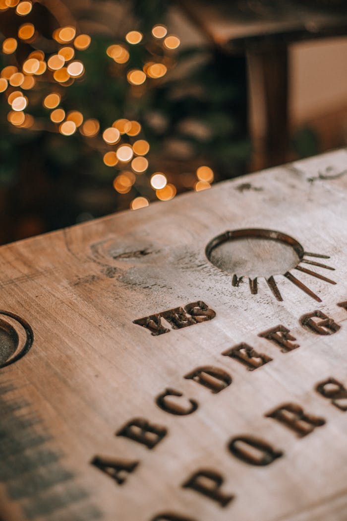 Close-up of a wooden Ouija board with decorative bokeh lights in the background.