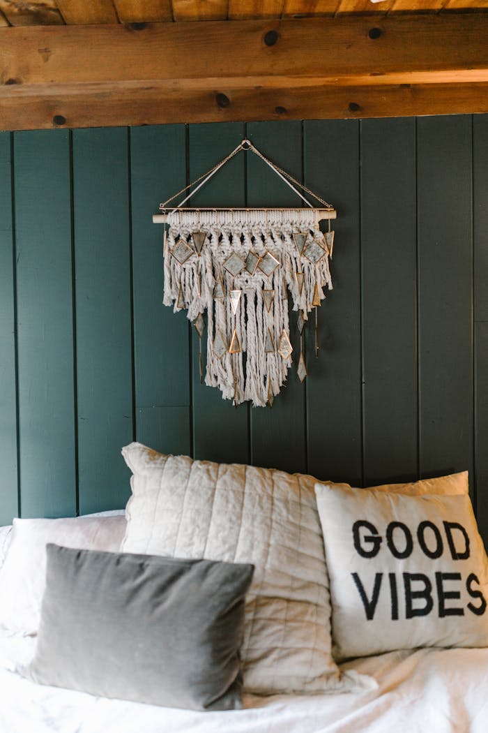 Cozy bedroom featuring a stylish macramé wall hanging and a pillow with Good Vibes text.