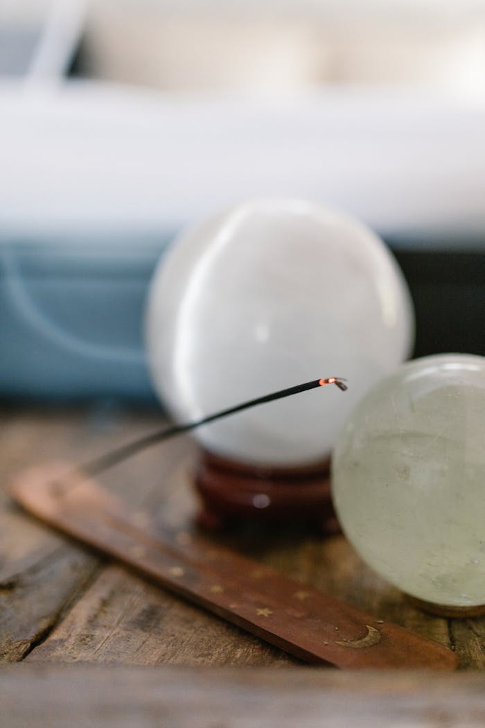 Serene still life with crystal balls and incense stick on rustic wood surface.